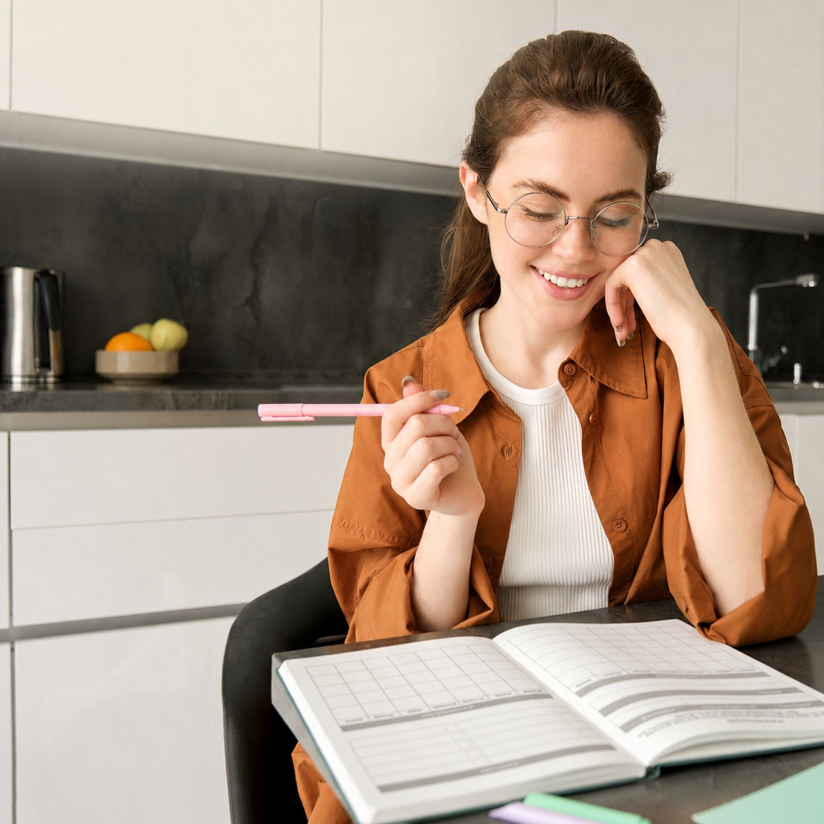 Vrouw met pen bij de opengeslagen HuysPlan budget planner aan de keukentafel