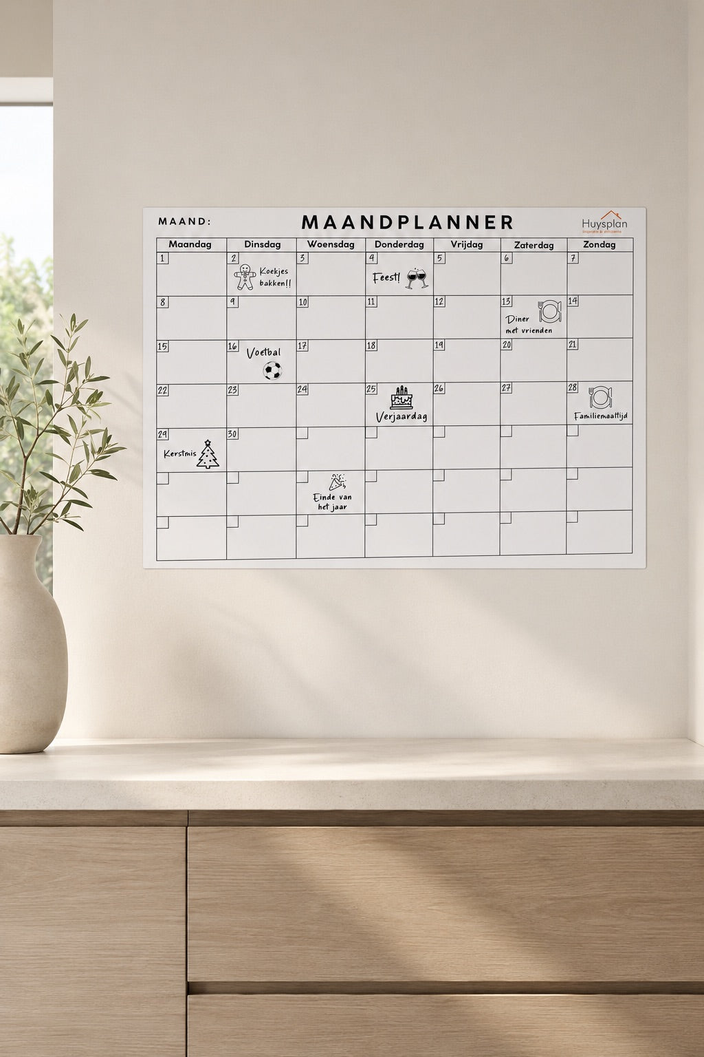 Zelfklevende maandplanner van HuysPlan op de muur boven een houten dressoir